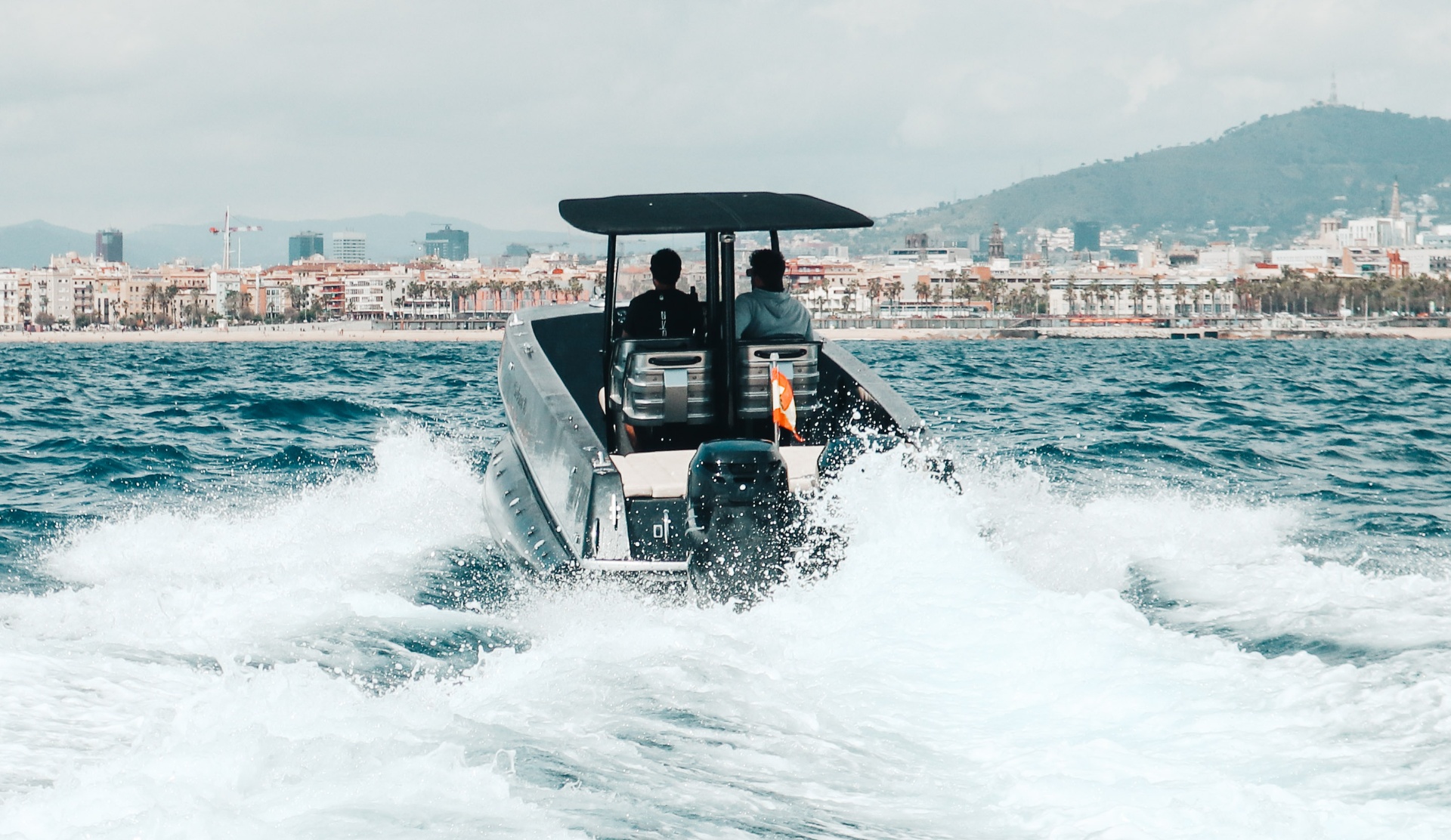 F11 Buzzi running fast off Barcelona with twin Mercury outboards throwing spray