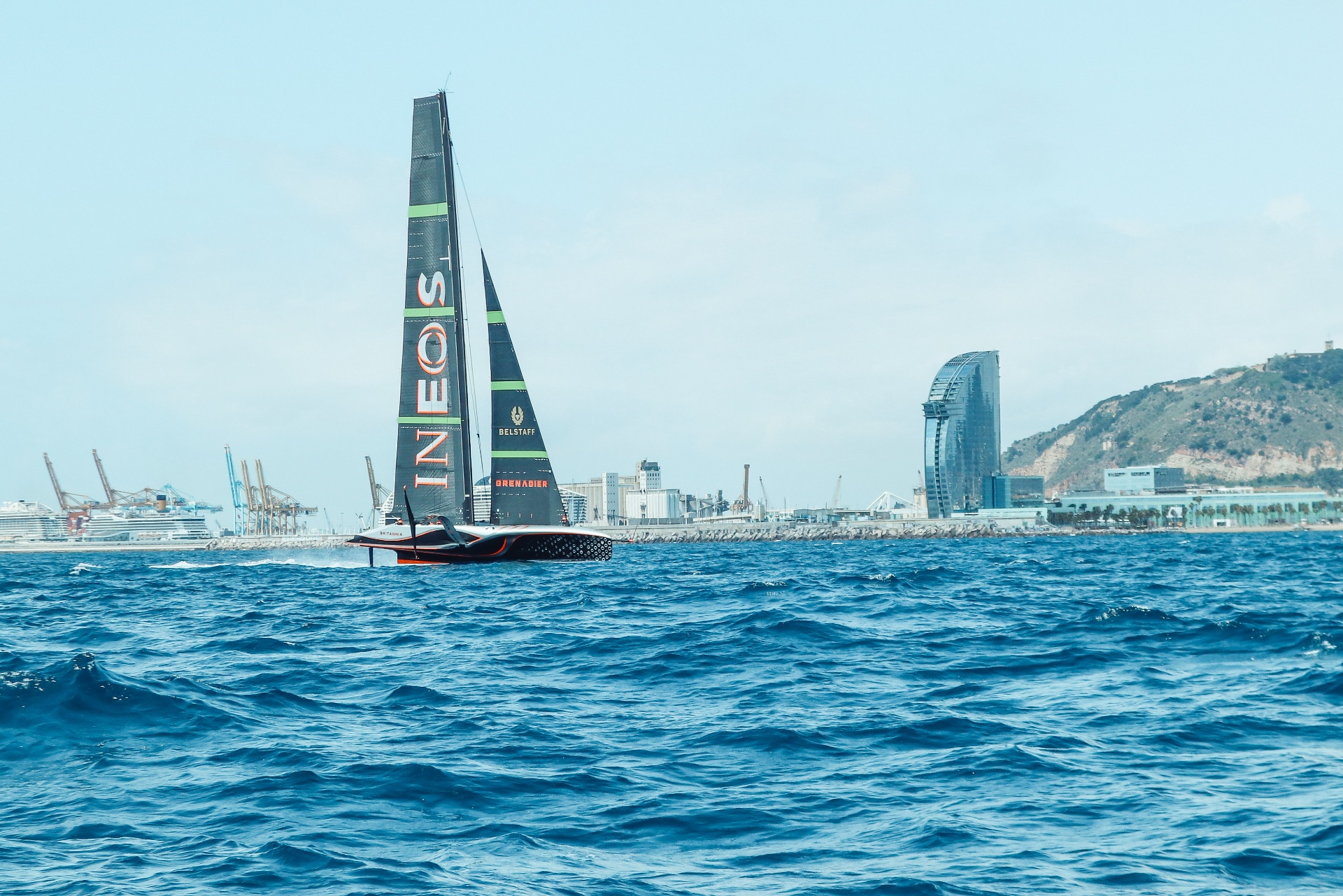 INEOS Britannia sailing past the W Barcelona skyline