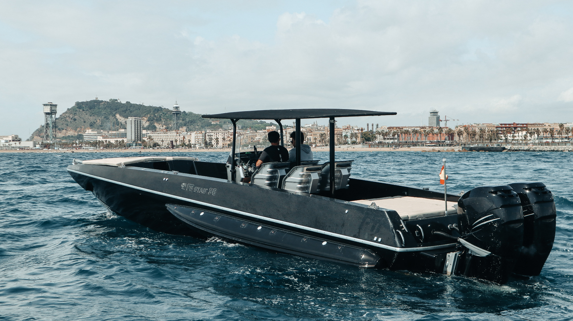 F11 Buzzi FB STAB 38 al ralentí frente a la Barceloneta con Montjuïc detrás